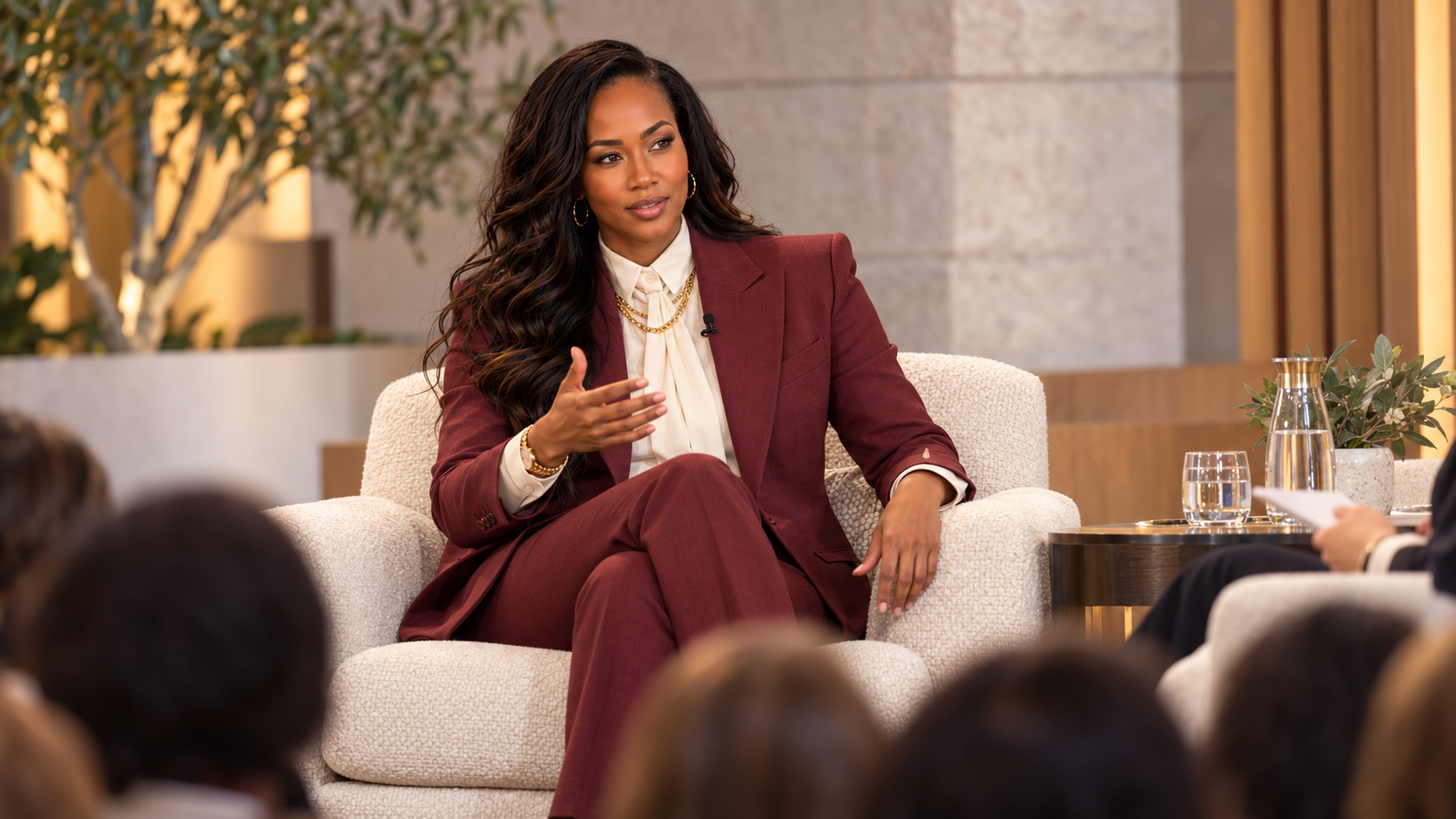 Kay Bowman on a panel in a burgundy suit, speaking to an audience